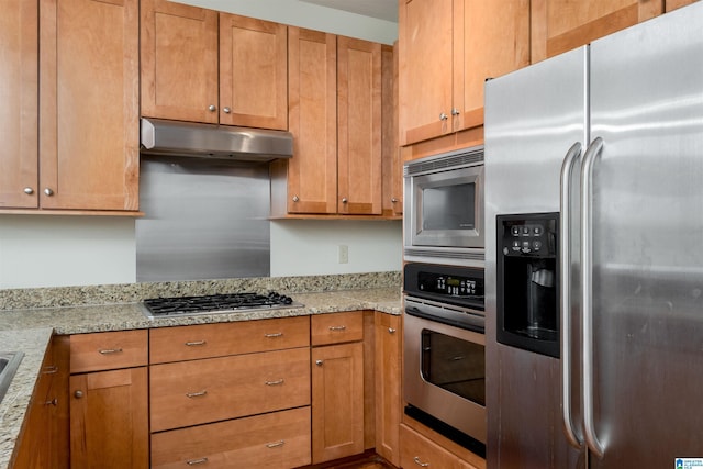 kitchen featuring stainless steel appliances, brown cabinetry, light stone countertops, and under cabinet range hood