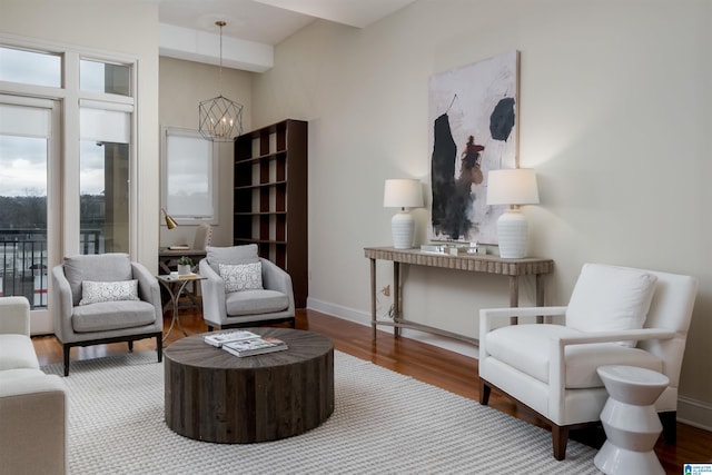 sitting room with a chandelier, baseboards, and wood finished floors