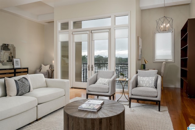 living area featuring baseboards, wood finished floors, and an inviting chandelier