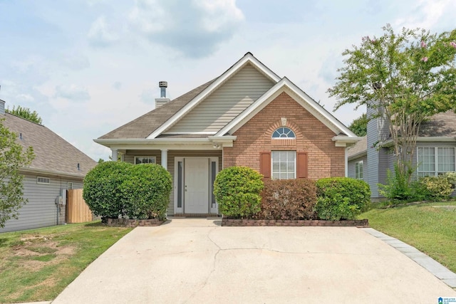 view of front of home with brick siding, fence, and a front lawn