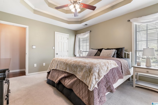 bedroom featuring baseboards, a tray ceiling, light carpet, and crown molding