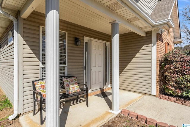 entrance to property with covered porch and a shingled roof