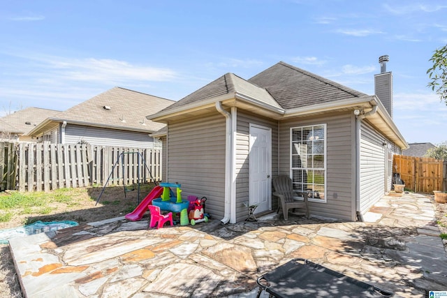 back of house featuring a patio, a shingled roof, a chimney, and a fenced backyard