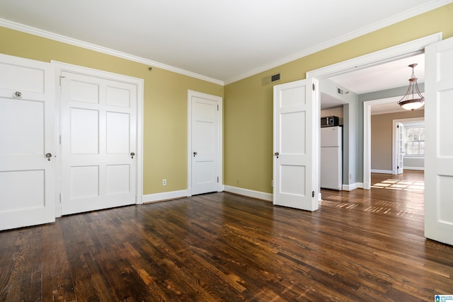 unfurnished bedroom with dark wood-style floors, visible vents, ornamental molding, freestanding refrigerator, and baseboards