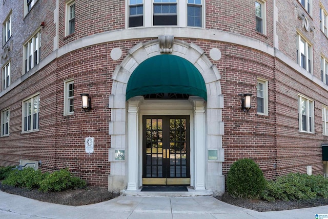 view of exterior entry featuring brick siding and french doors