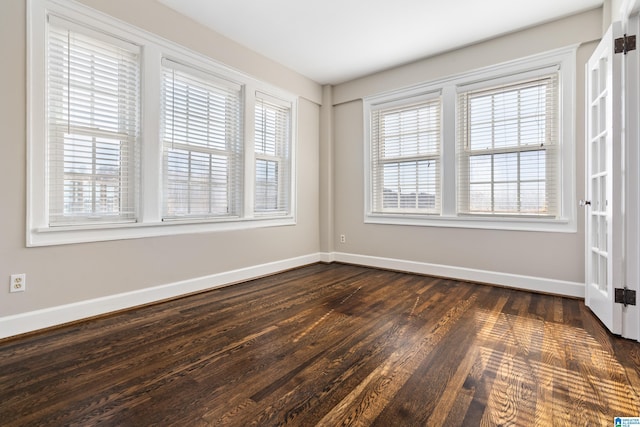 unfurnished room with dark wood finished floors and baseboards