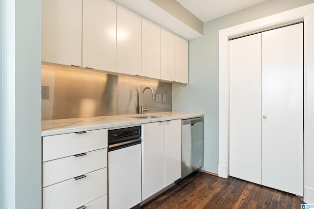 kitchen featuring white cabinets, dishwasher, dark wood-type flooring, light stone countertops, and a sink