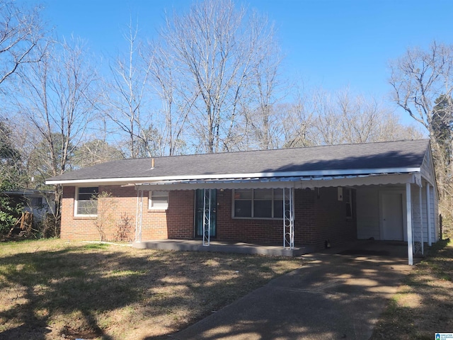 ranch-style home with a carport, brick siding, a front lawn, and driveway