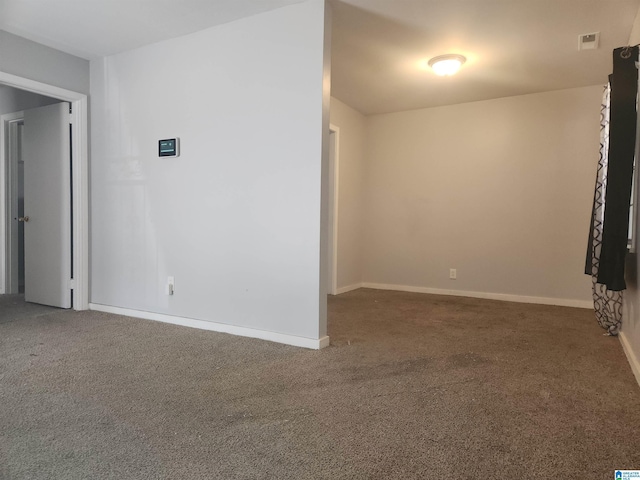 spare room with carpet floors, visible vents, and baseboards