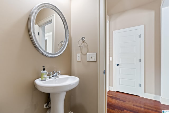 bathroom with wood finished floors, baseboards, and a sink