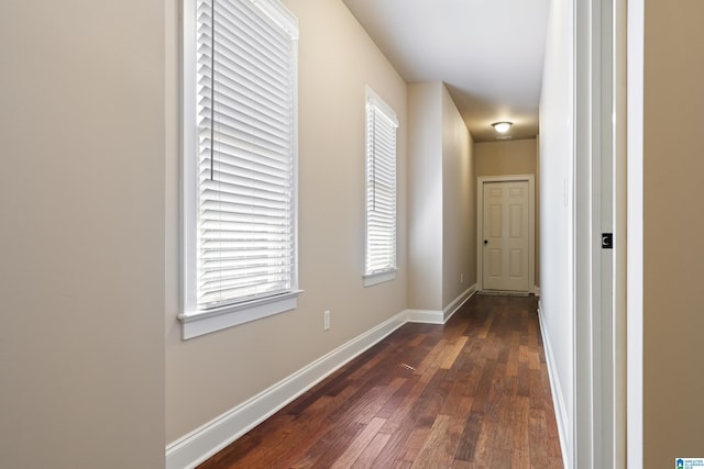 corridor with baseboards and dark wood finished floors