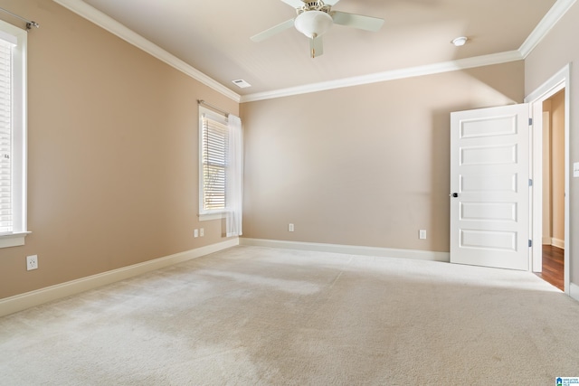 carpeted spare room with visible vents, baseboards, ceiling fan, and ornamental molding