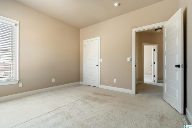 unfurnished bedroom with baseboards and light colored carpet