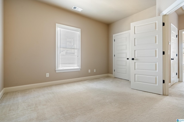 unfurnished bedroom with visible vents, light carpet, and baseboards