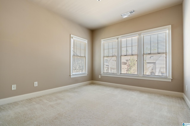 empty room with visible vents, baseboards, and light colored carpet