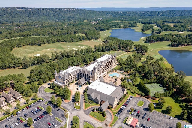 aerial view featuring a wooded view, golf course view, and a water view