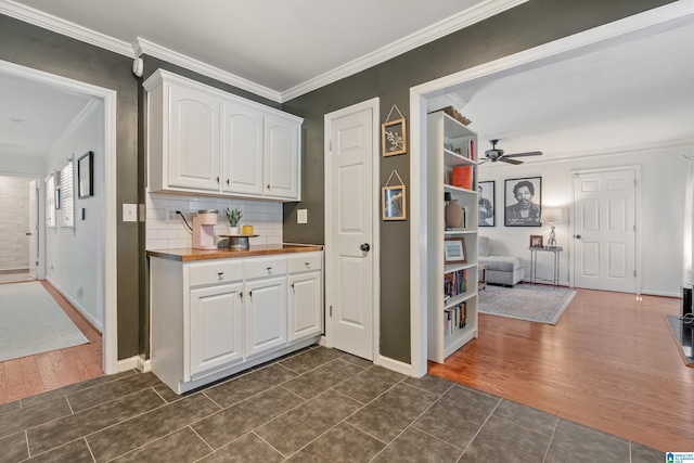 kitchen with backsplash, crown molding, white cabinetry, a ceiling fan, and dark wood-style flooring