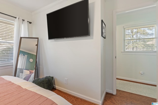 bedroom with crown molding, wood finished floors, and baseboards