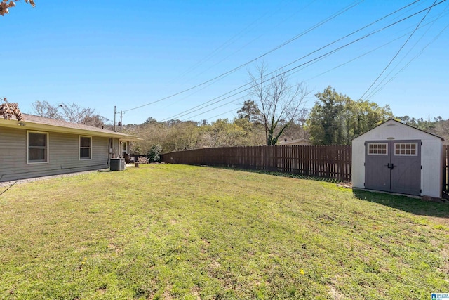 view of yard with a storage shed, cooling unit, fence, and an outbuilding