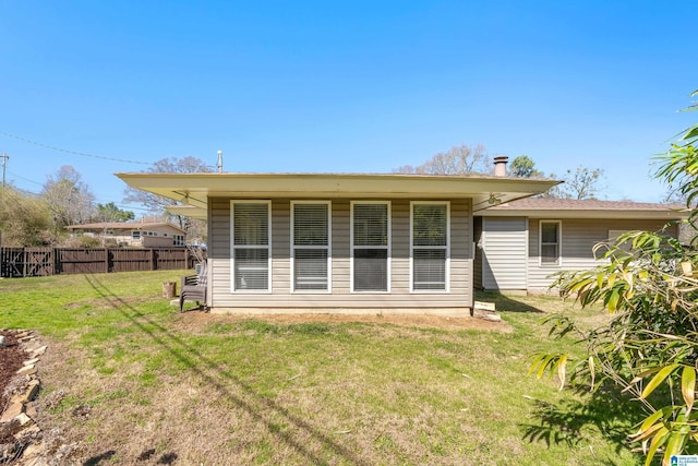 back of house featuring fence and a lawn