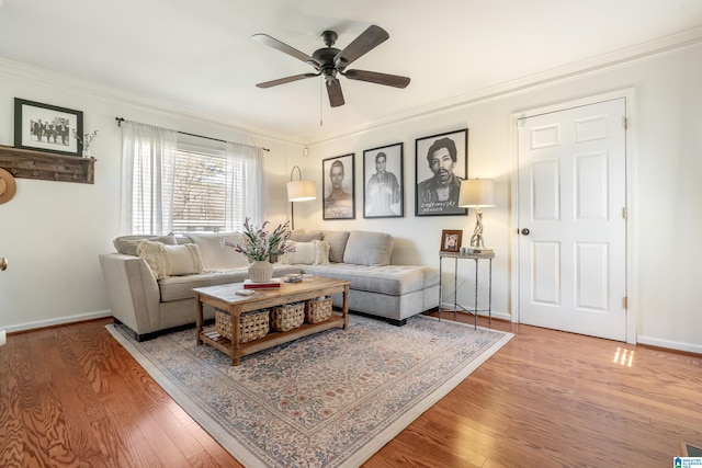 living area with crown molding, wood finished floors, baseboards, and ceiling fan