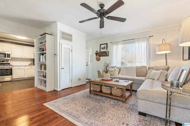 living area with baseboards, crown molding, a ceiling fan, and wood finished floors