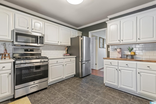 kitchen featuring light countertops, white cabinets, appliances with stainless steel finishes, crown molding, and tasteful backsplash