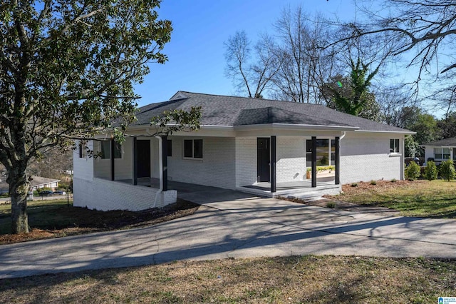 view of front of house featuring concrete driveway, brick siding, and a shingled roof