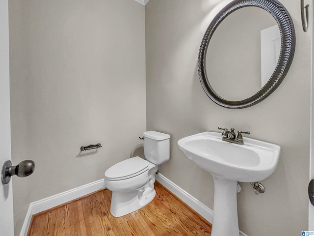 half bathroom featuring toilet, baseboards, and wood finished floors