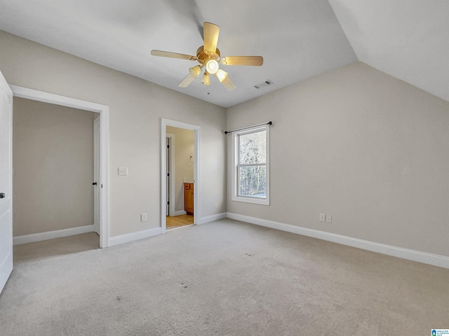 unfurnished bedroom featuring baseboards, visible vents, vaulted ceiling, ensuite bathroom, and light carpet