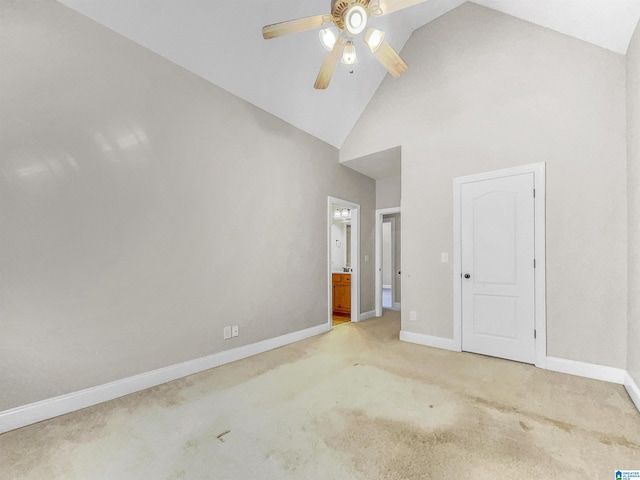 unfurnished bedroom featuring high vaulted ceiling, light colored carpet, ensuite bath, and baseboards