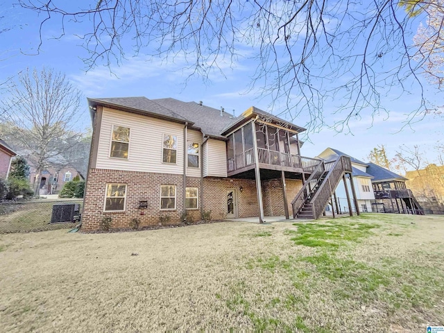 back of property with fence, stairway, a yard, a sunroom, and brick siding