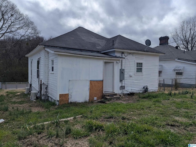 back of property featuring entry steps, central AC, fence, and a lawn