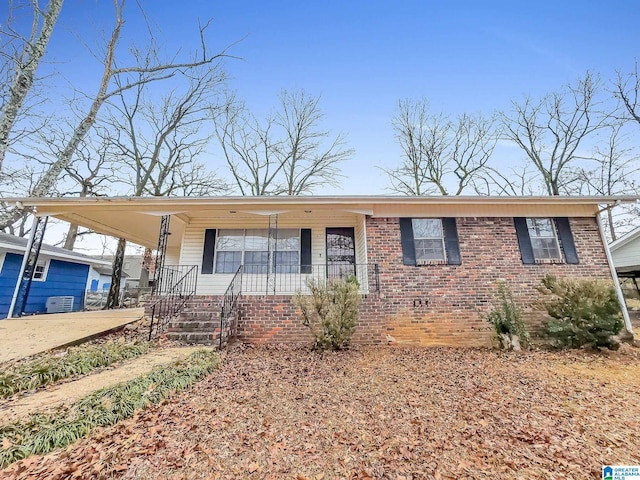 view of front of home with a porch, concrete driveway, brick siding, and a carport