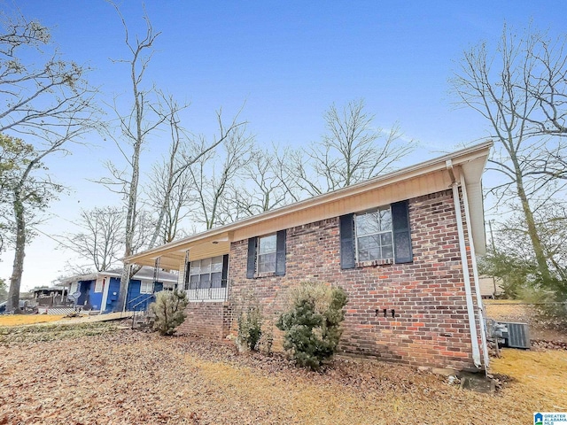 view of front facade featuring a carport, brick siding, and central AC unit