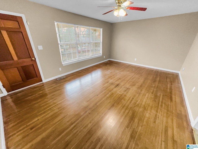 unfurnished room featuring a ceiling fan, wood finished floors, visible vents, and baseboards