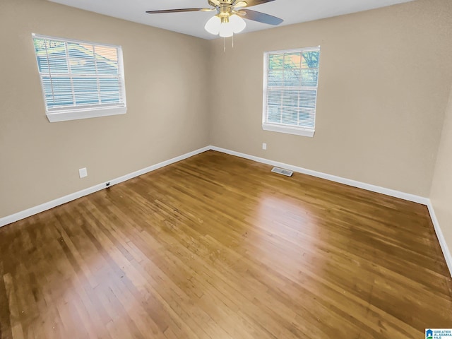 spare room featuring baseboards, visible vents, and wood finished floors