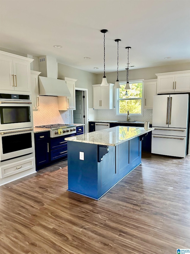 kitchen with white appliances, a kitchen island, custom exhaust hood, white cabinets, and blue cabinets