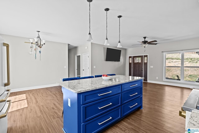 kitchen with open floor plan, blue cabinetry, ceiling fan with notable chandelier, and wood finished floors