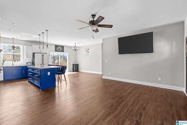 kitchen featuring blue cabinets, a kitchen bar, a center island, freestanding refrigerator, and a healthy amount of sunlight