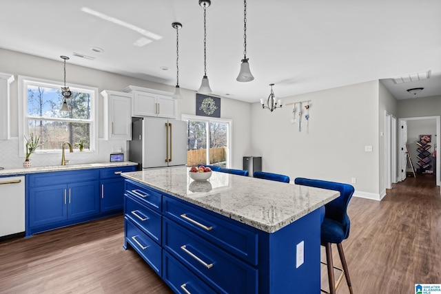 kitchen with visible vents, blue cabinetry, white appliances, and a kitchen bar