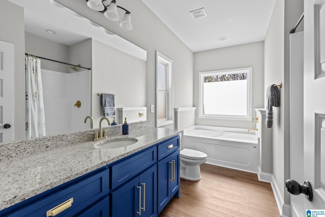 bathroom with visible vents, toilet, wood finished floors, a bath, and vanity