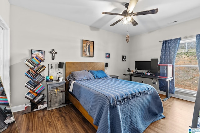 bedroom with a ceiling fan, wood finished floors, visible vents, and baseboards