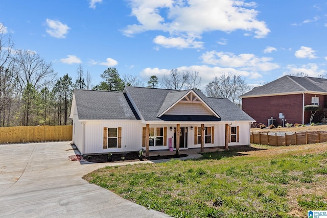 view of front of home with a porch, fence, driveway, and roof with shingles