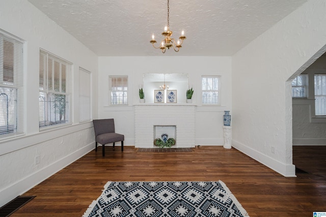 foyer featuring a fireplace, visible vents, a textured wall, an inviting chandelier, and wood finished floors