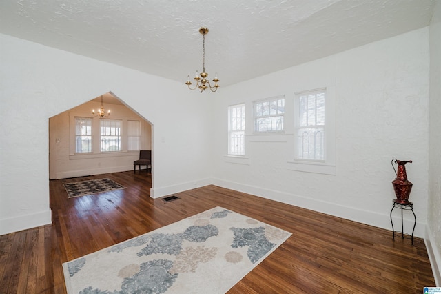 interior space with a healthy amount of sunlight, an inviting chandelier, visible vents, and wood finished floors