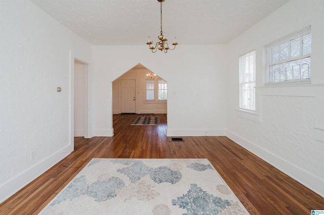 dining space featuring baseboards, visible vents, wood finished floors, a textured ceiling, and a chandelier