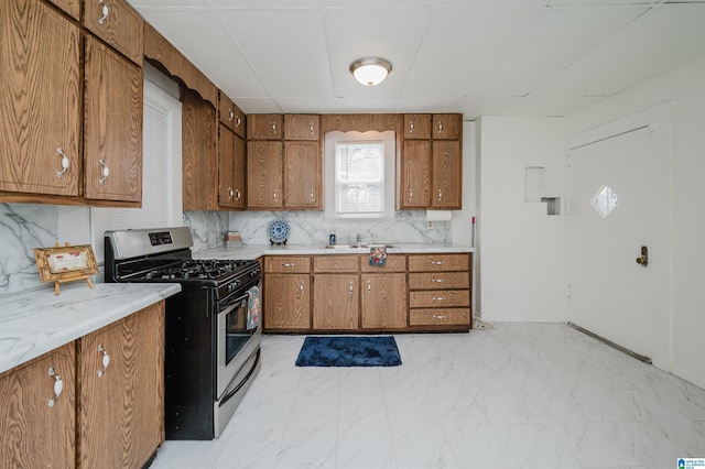 kitchen featuring a sink, light countertops, brown cabinetry, and stainless steel range with gas cooktop