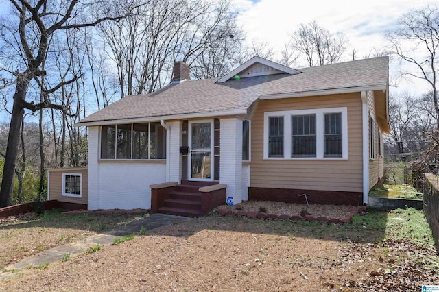 bungalow-style home featuring entry steps, a chimney, roof with shingles, fence, and brick siding