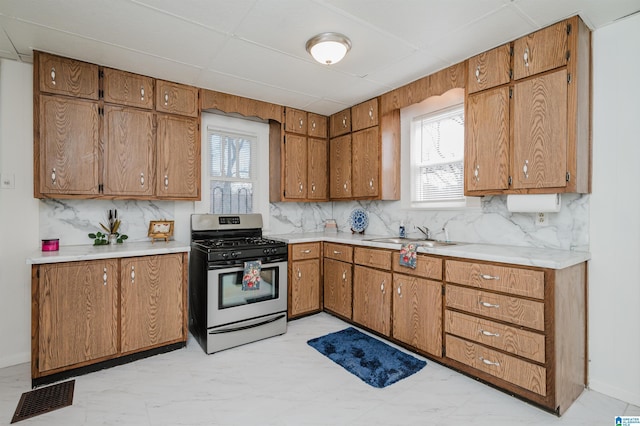 kitchen featuring visible vents, stainless steel gas range, a sink, and a wealth of natural light